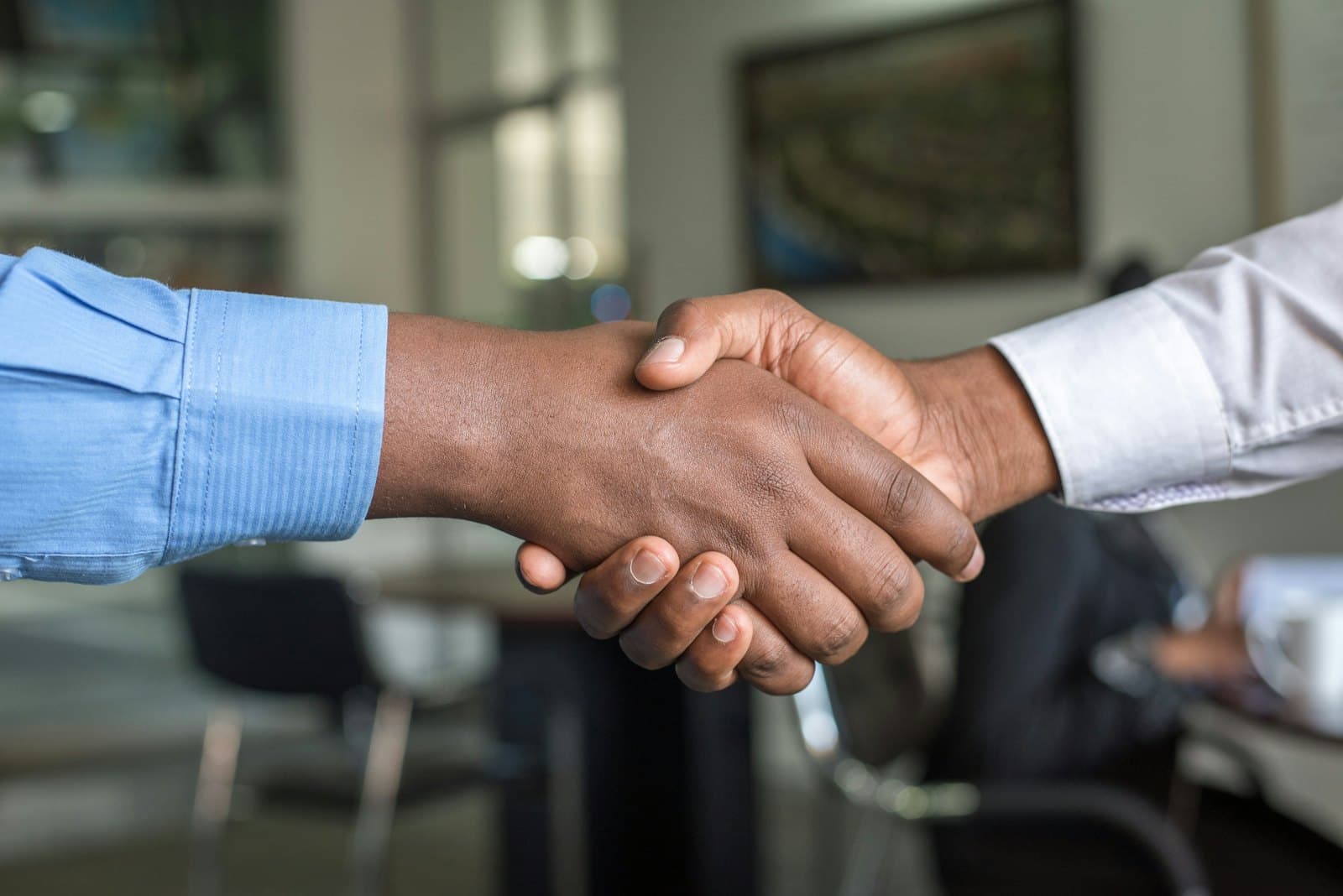 Two people shaking hands across an office table after a hiring decision