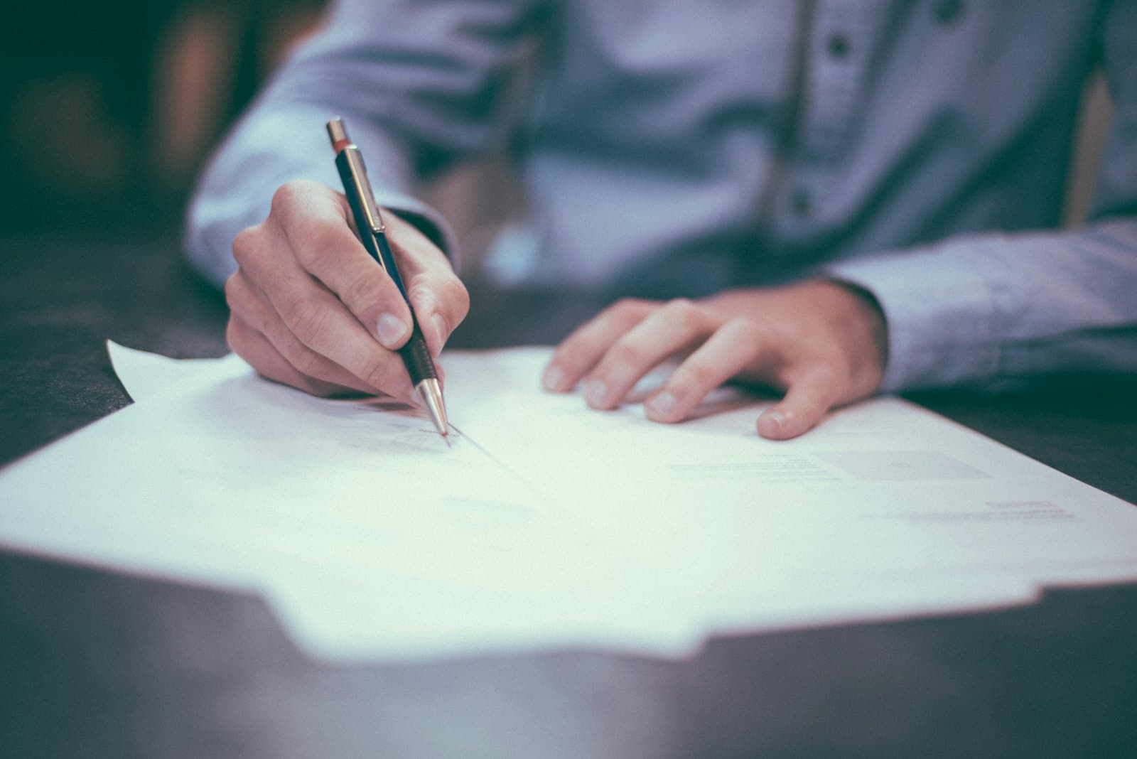 A person reviewing and signing verification documents at a desk